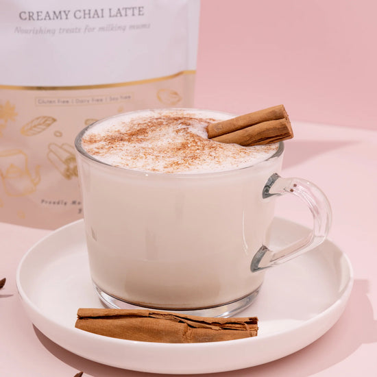 Glass mug of lactation creamy chai latte with cinnamon stick on a pink background made to milk creamy chai latte