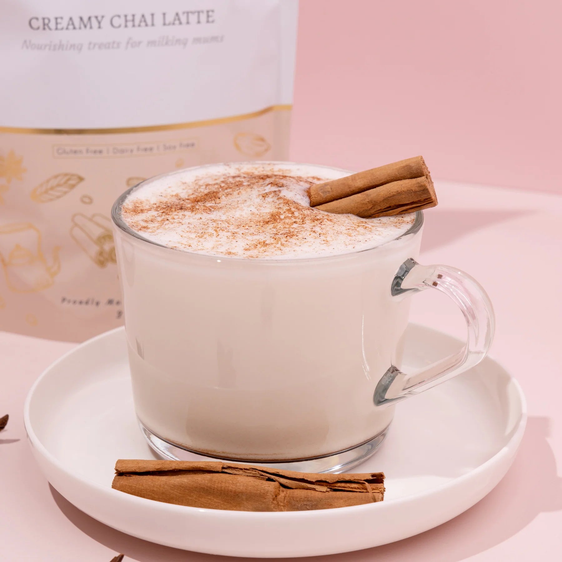 Glass mug of lactation creamy chai latte with cinnamon stick on a pink background made to milk creamy chai latte