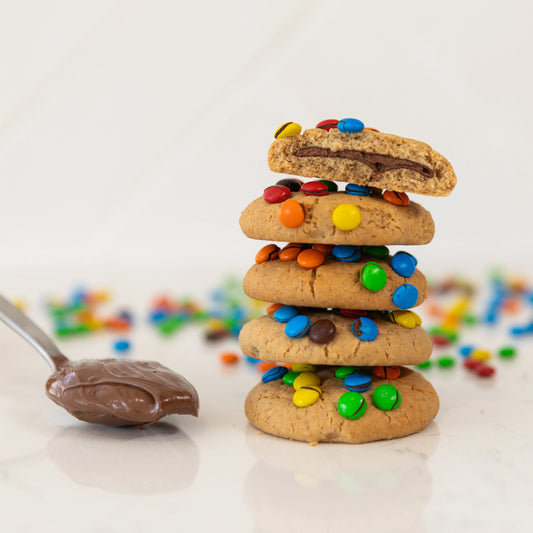 Stack of cookies with mini m&ms and a spoonful of nutella on a light background