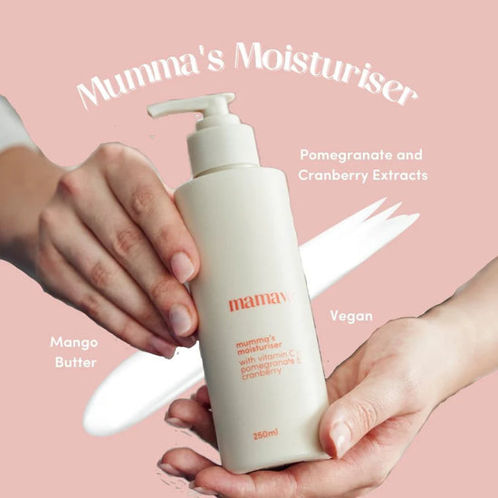 Mumma's Moisturiser bottle held by hands with a pink background saying pomegranate and cranberry extracts, vegan and mango butter