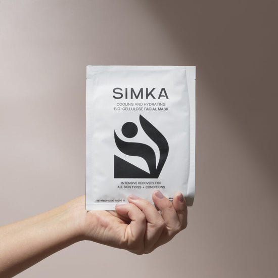 Hand holding a SIMKA facial mask package against a neutral background