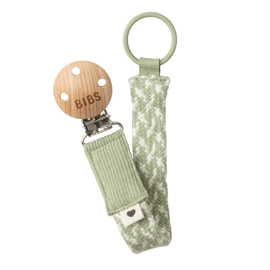 Dummy clip or Pacifier clip. Light timber badge that says bibs on top of metal clip attached. Braided cotton band in ivory and sage with dummy ring on end.