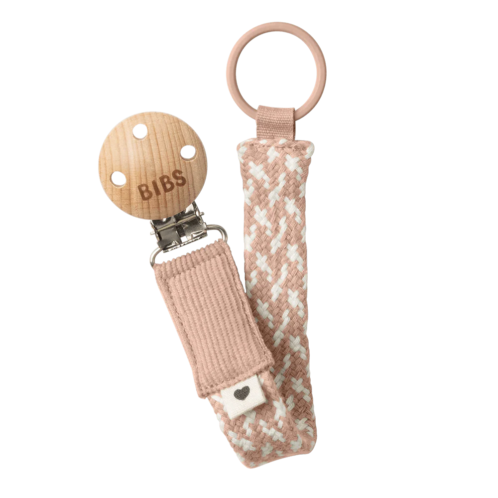 Dummy clip or Pacifier clip. Light timber badge that says bibs on top of metal clip attached. Braided cotton band in ivory and blush with dummy ring on end.