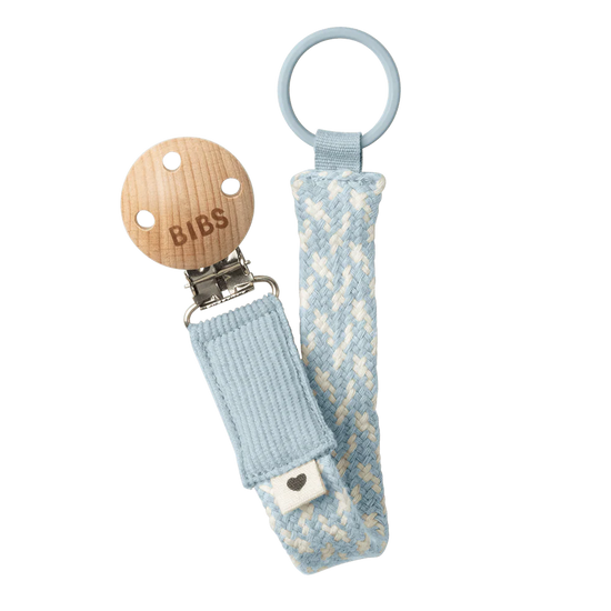 Dummy clip or Pacifier clip. Light timber badge that says bibs on top of metal clip attached. Braided cotton band in ivory and baby blue with dummy ring on end.