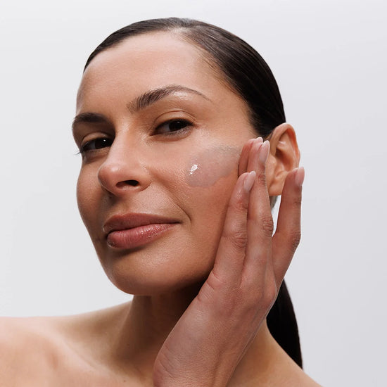 Woman applying algizome to her face with a neutral background
