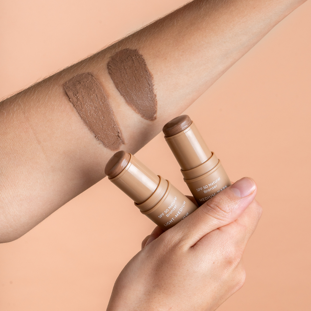 Two contour sticks avozinc with swatches on a person's arm against a beige background