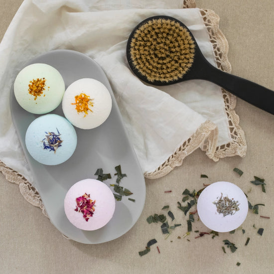 Wheelers Hill soap bath bombs with natural ingredients on a tray next to a brush and cloth on a beige surface