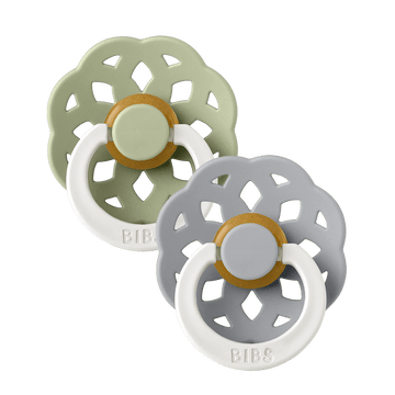 Set of two BIBS Boheme pacifiers featuring sage and blue colours, flower-style silicone shields, and white ring handles—premium baby soothers for newborns and infants. Glow in the dark, round, size one.