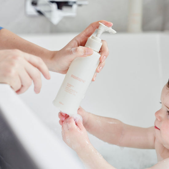 Person applying Bubba's Wash pump bottle of  product to a child's hand in a bubble bath bathroom setting.