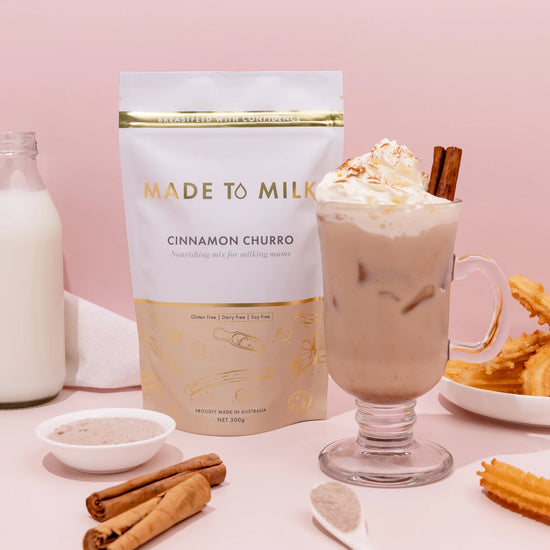 Made to Milk cinnamon churro flavor packaging with a glass of hot chocolate and cinnamon sticks on a pink background