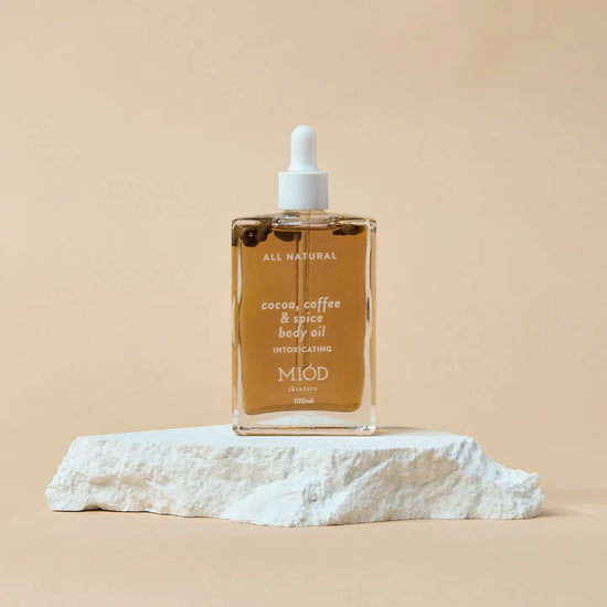 Bottle of MIOD cocoa, coffee & spice body oil on a beige background