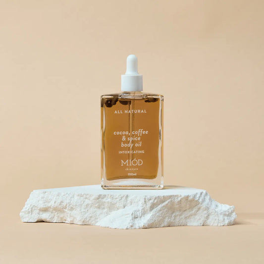 Bottle of MIOD cocoa, coffee & spice body oil on a beige background