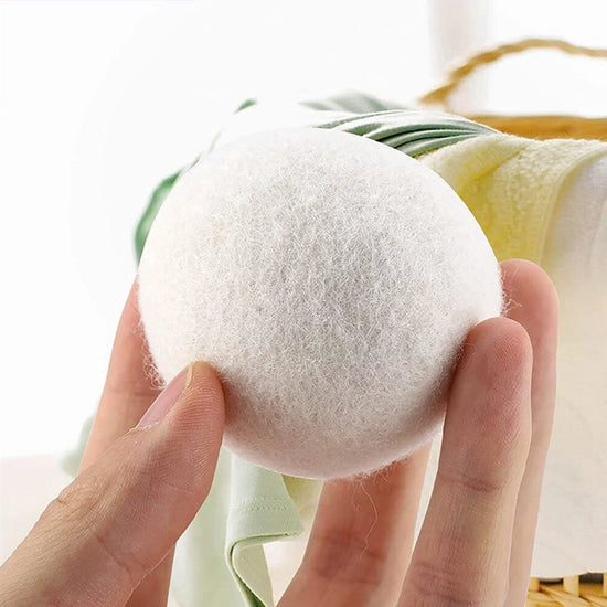 Dryer ball held between fingers with a blurred background