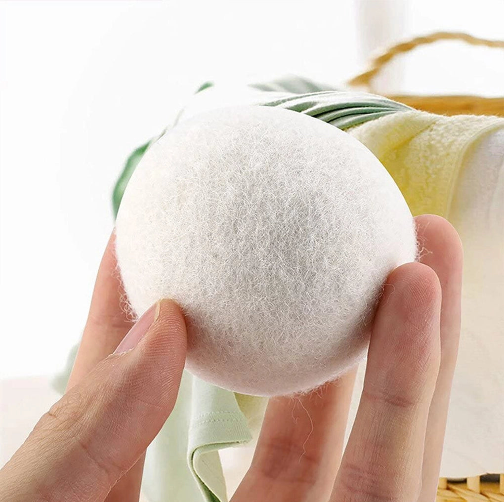 Dryer ball held between fingers with a blurred background