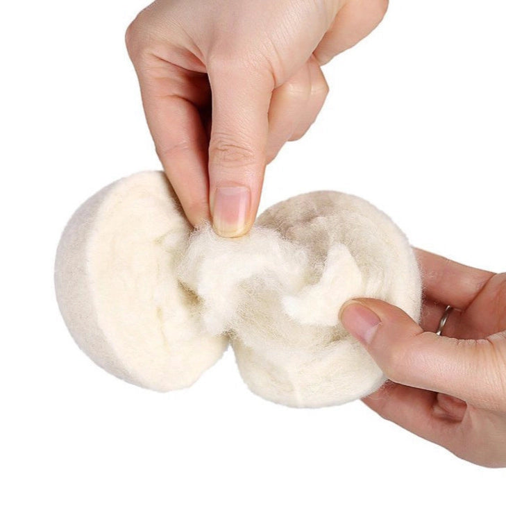 Two fluffy white balls held by a hand against