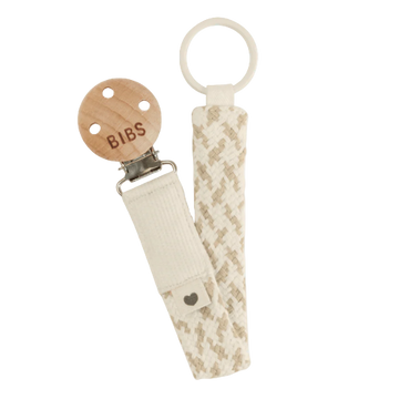 Dummy clip or Pacifier clip. Light timber badge that says bibs on top of metal clip attached. Braided cotton band in ivory and vanilla with dummy ring on end. 