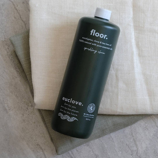 Dark green bottle labeled 'floor.' and 'euclove.' on a textured surface