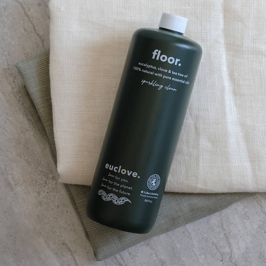 Dark green bottle labeled 'floor.' and 'euclove.' on a textured surface