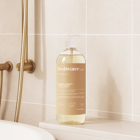 Bottle of Freshwater manuka honey and vanilla bean soap on a bathroom shelf with tiled wall background