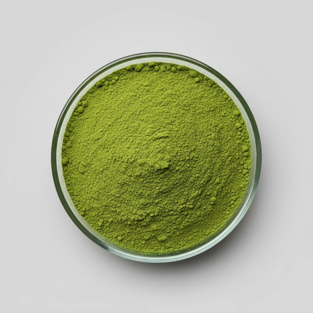 Green genmaicha powder in a glass bowl on a light gray background