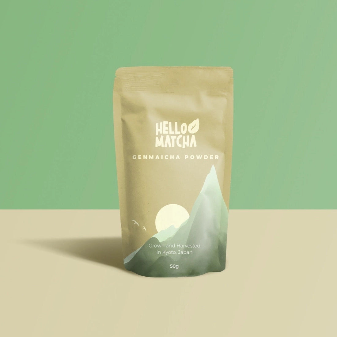 Packaging of Hello Matcha Genmaicha Powder on a beige surface with a green background