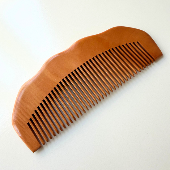 Brown wooden labour & birthing comb on white background