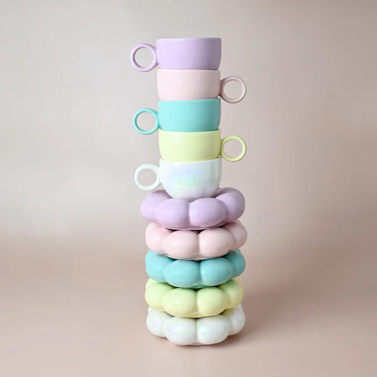 Stack of colorful mugs and matching saucers on a beige background