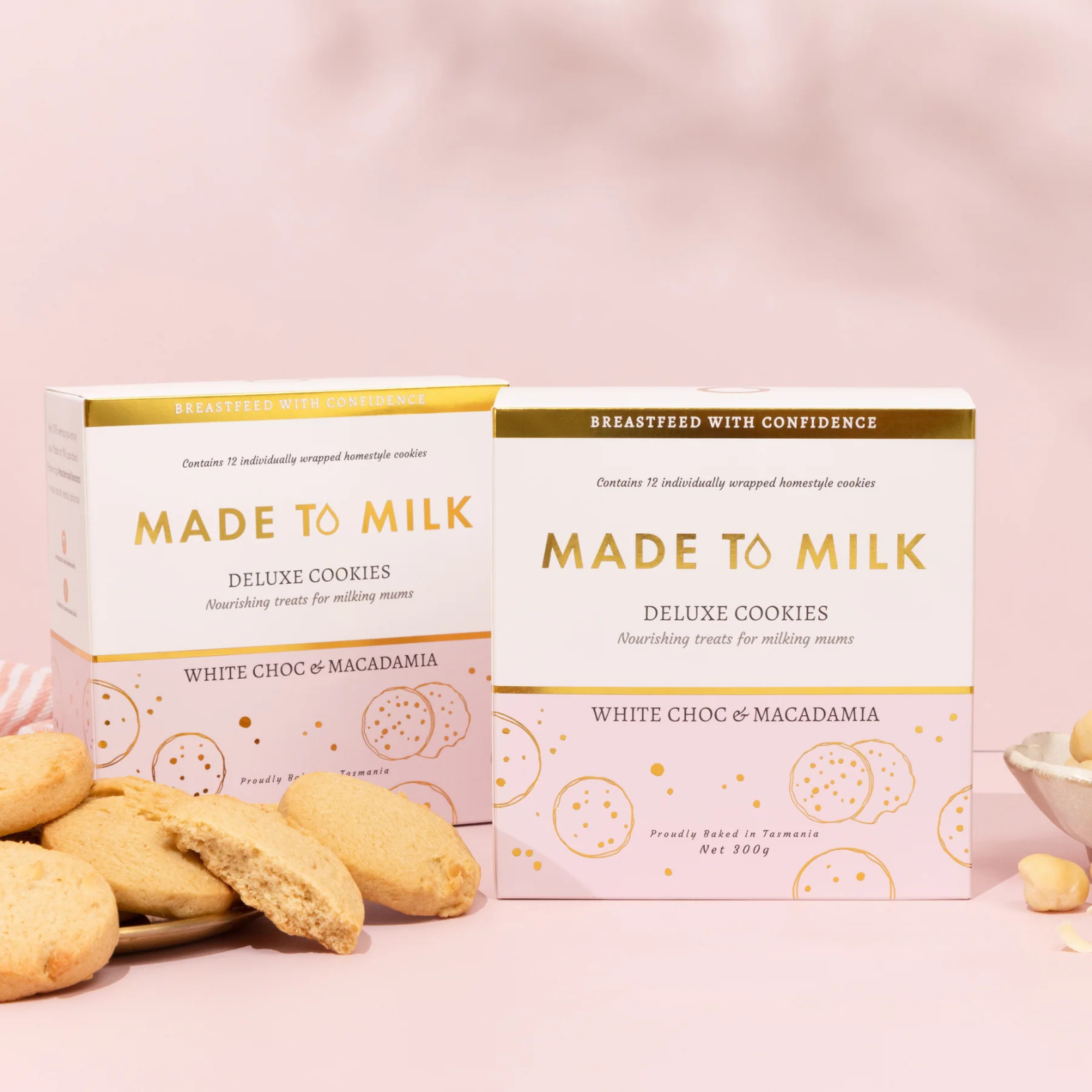 Two boxes of 'Made to Milk' deluxe white choc & macadamia cookies on a pink background