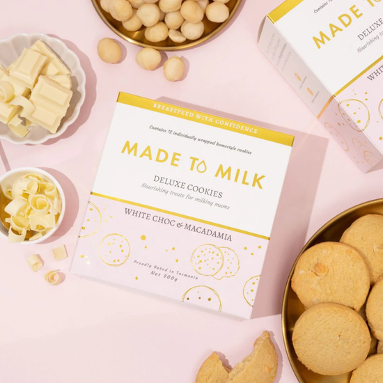 Made to Milk white choc & macadamia deluxe cookies packaging with cookies and ingredients on a pink background