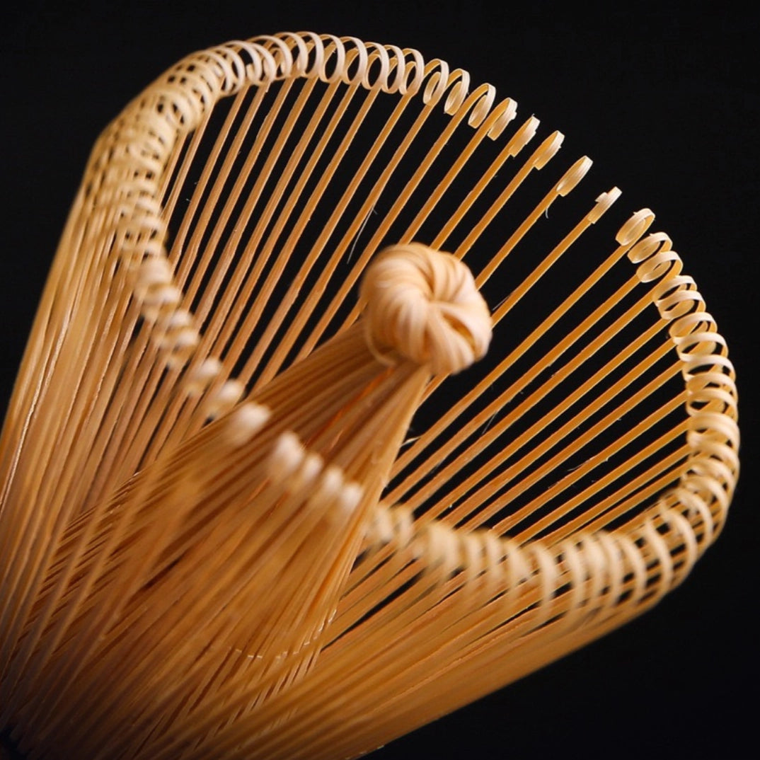 Woven whisk with a handle on a black background