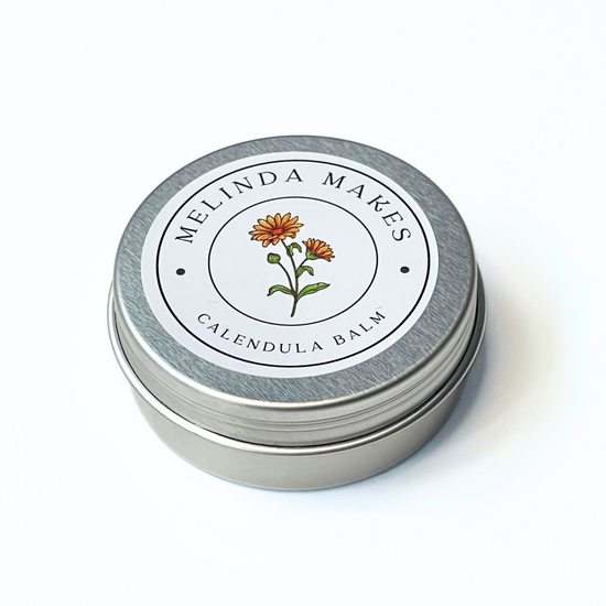 Metal tin with 'Melinda Makes' label featuring with calendula floral design on a white background