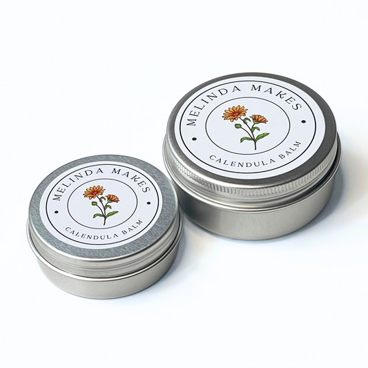 Both size tins of Melinda Makes Calendula Balm with calendula floral on it on a white background