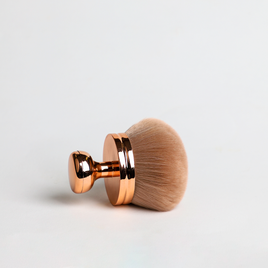 Makeup brush with rose gold handle on white background
