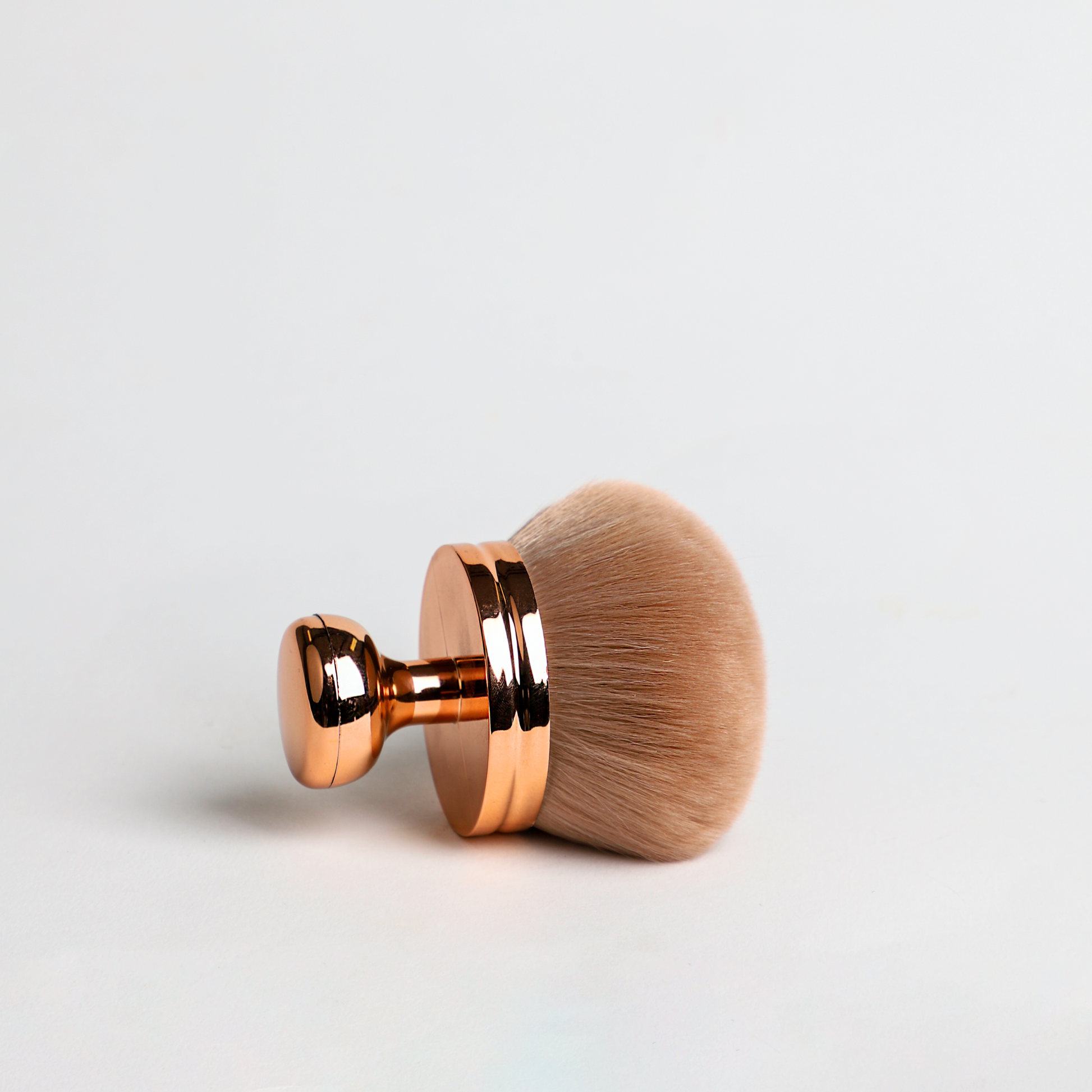 Makeup brush with rose gold handle on white background