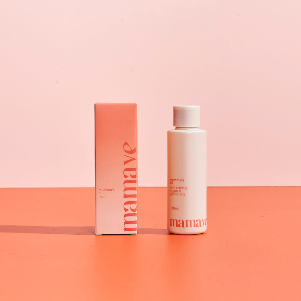 Mamave Mumma's Pregnancy and Postpartum Oil product packaging in bottle and box on a two-tone pink background