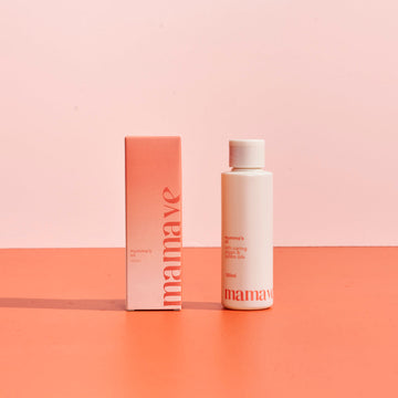 Mamave Mumma's Pregnancy and Postpartum Oil product packaging in bottle and box on a two-tone pink background