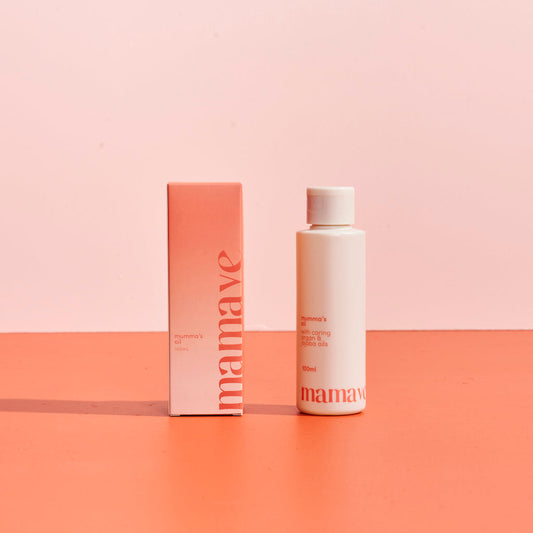 Mamave Mumma's Pregnancy and Postpartum Oil product packaging in bottle and box on a two-tone pink background