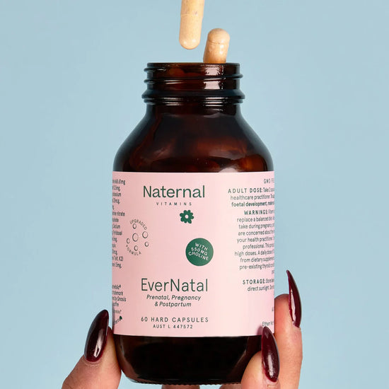 Brown bottle labeled 'EverNatal' held by a hand against a light blue background