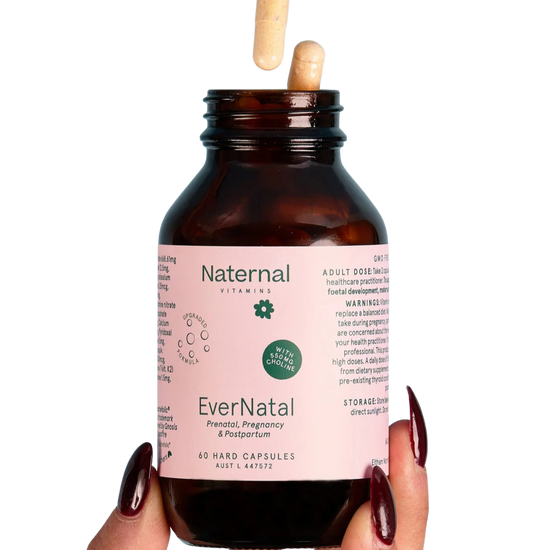 Bottle of Naternal EverNatal prenatal, pregnancy & postpartum vitamins held by a hand with dark nail polish 
