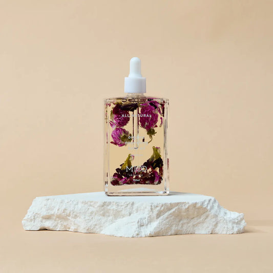 Bottle of floral oil with dried flowers on organic nourishing body oil a beige background with a stone