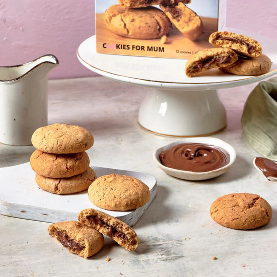 Lactation Nutella Cookies with Nutella filling on a marble surface with a 'Cookies for Mum' box in the background.