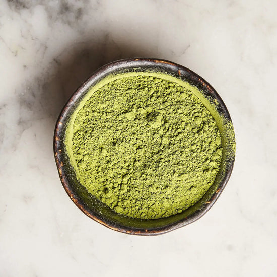 Bowl of green matcha powder on a marble surface