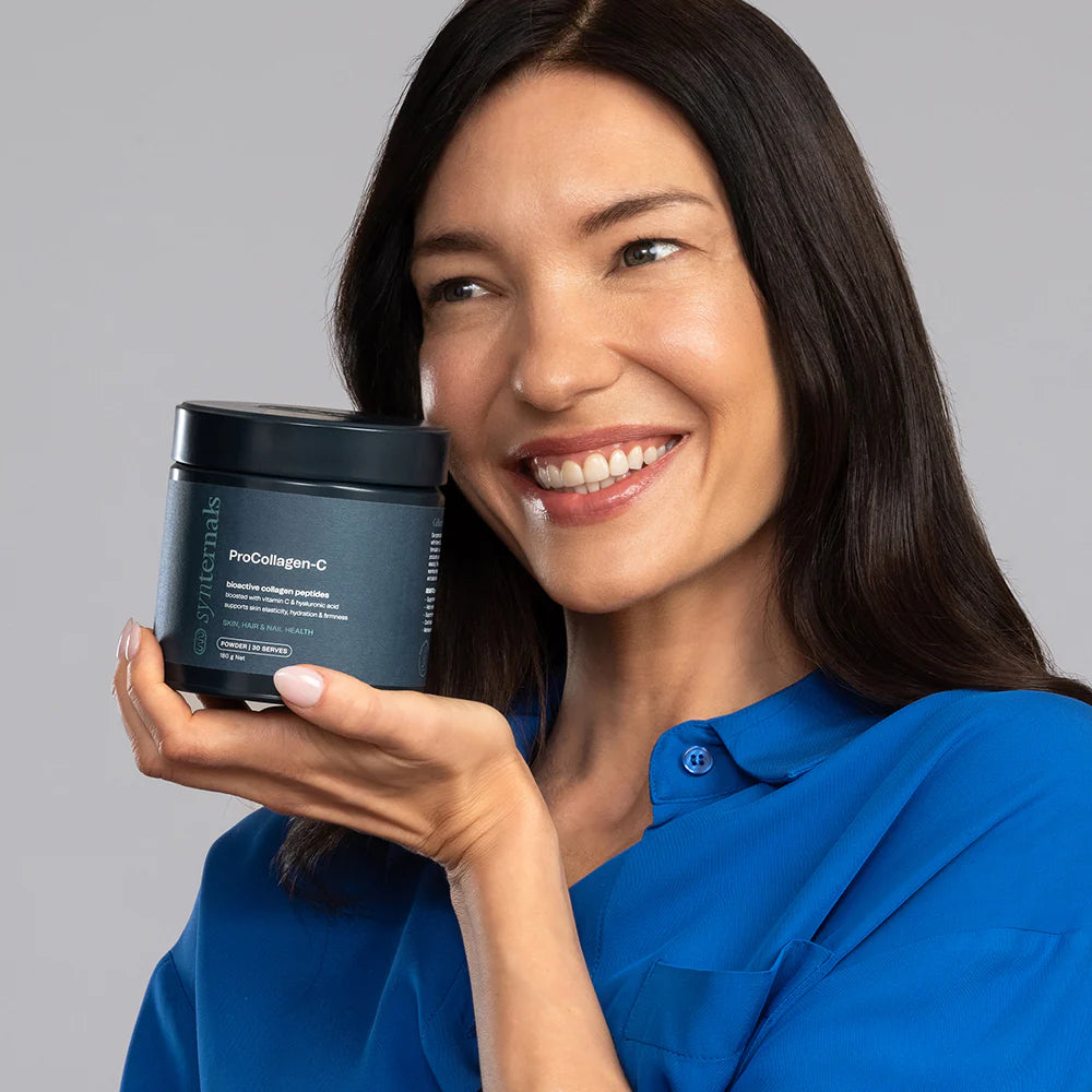 Woman holding a ProCollagen-C product container against a gray background
