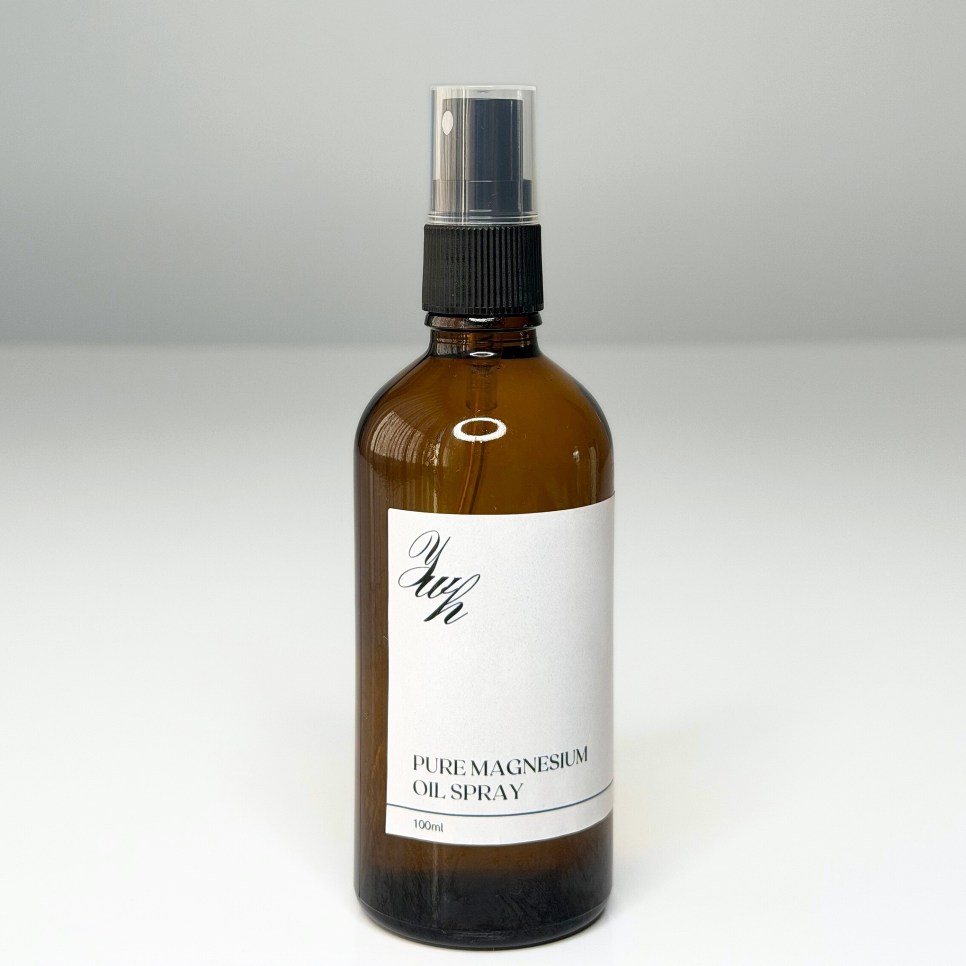 Brown glass bottle with black spray nozzle and white label on a gray background