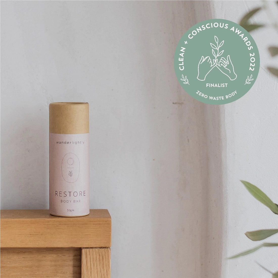 restore body bar in a cardboard tube on a wooden block with a 'Clean + Conscious Awards' finalist badge in the corner.