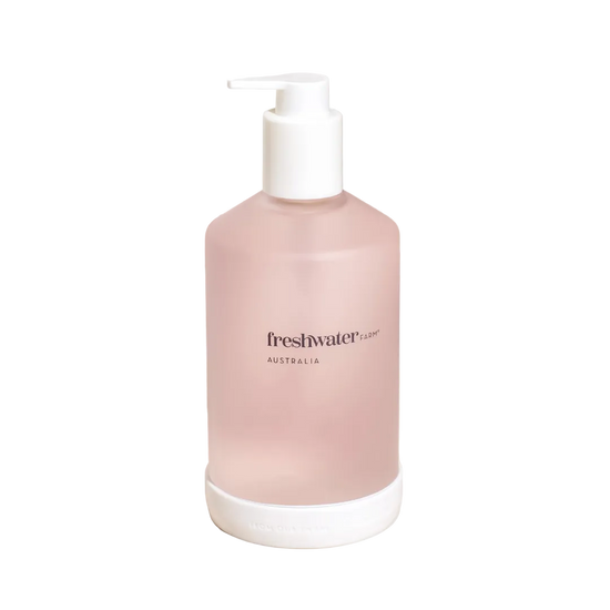 Pink bottle with pump dispenser on a beige surface