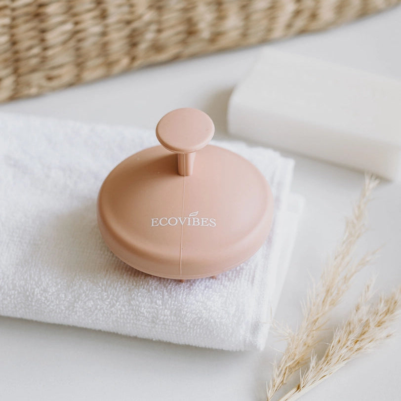 Pink bottle with 'ECOVIBES' branding on a white towel with a woven basket in the background.