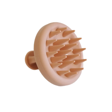 Peach-colored scalp massager on a light gray background
