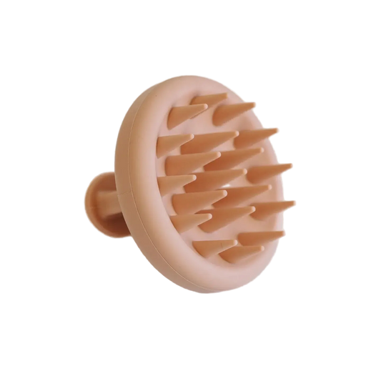 Peach-colored scalp massager on a light gray background