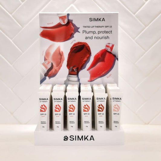 SIMKA lip care products displayed on a stand with promotional poster against a white tiled wall.